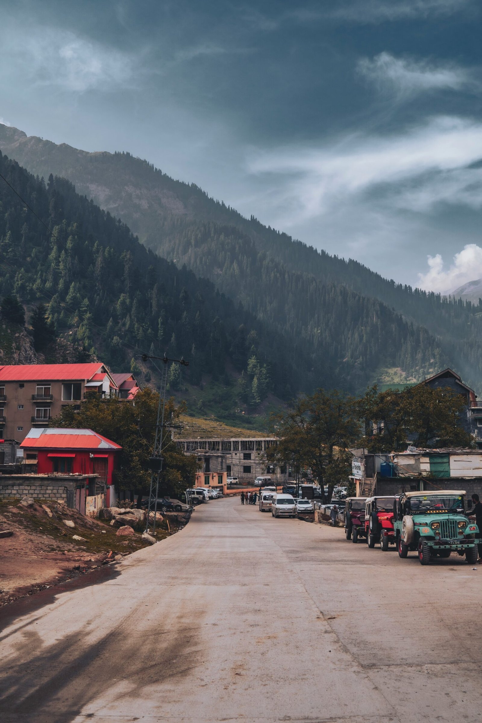 a road with cars and buildings by a mountain